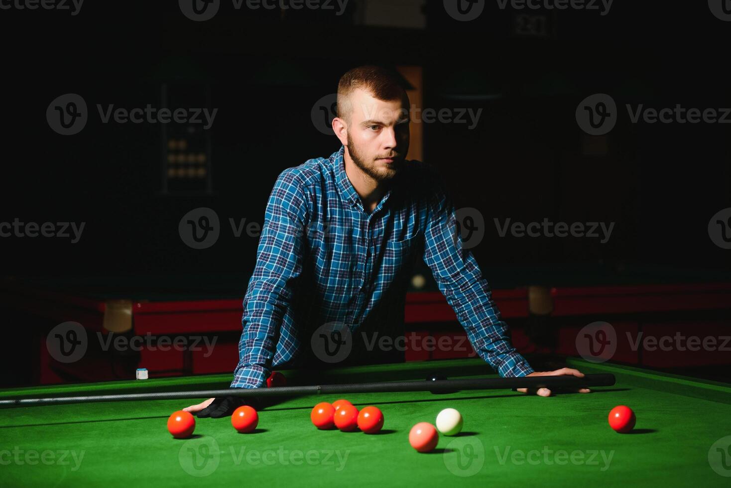 Young handsome man leaning over the table while playing snooker photo