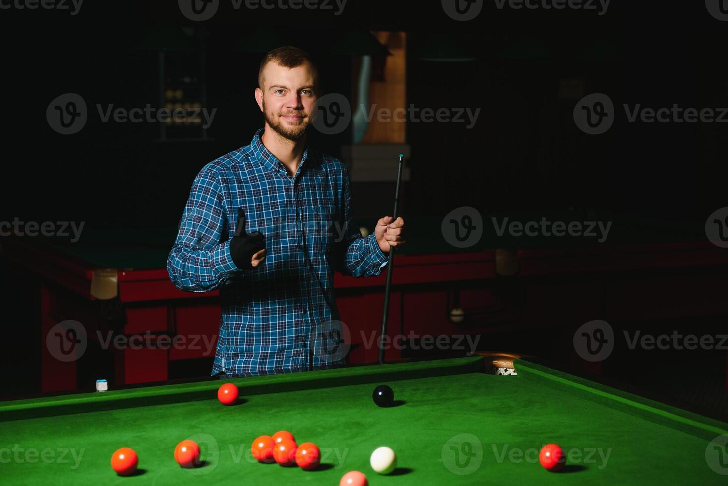 Young handsome man leaning over the table while playing snooker photo