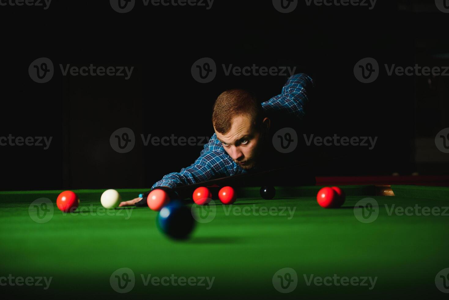Young handsome man leaning over the table while playing snooker photo
