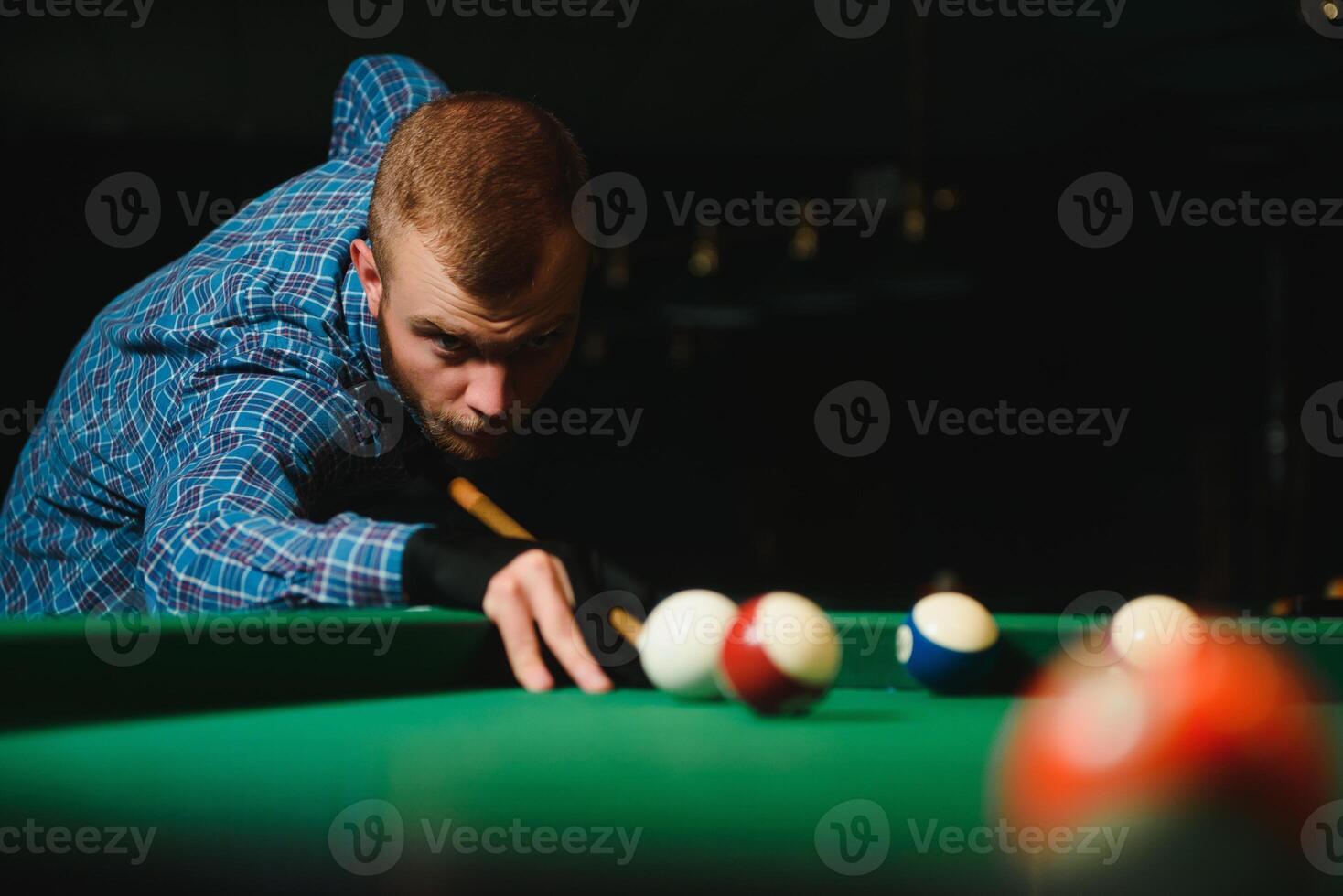 Young man playing billiards in the dark billiard club photo