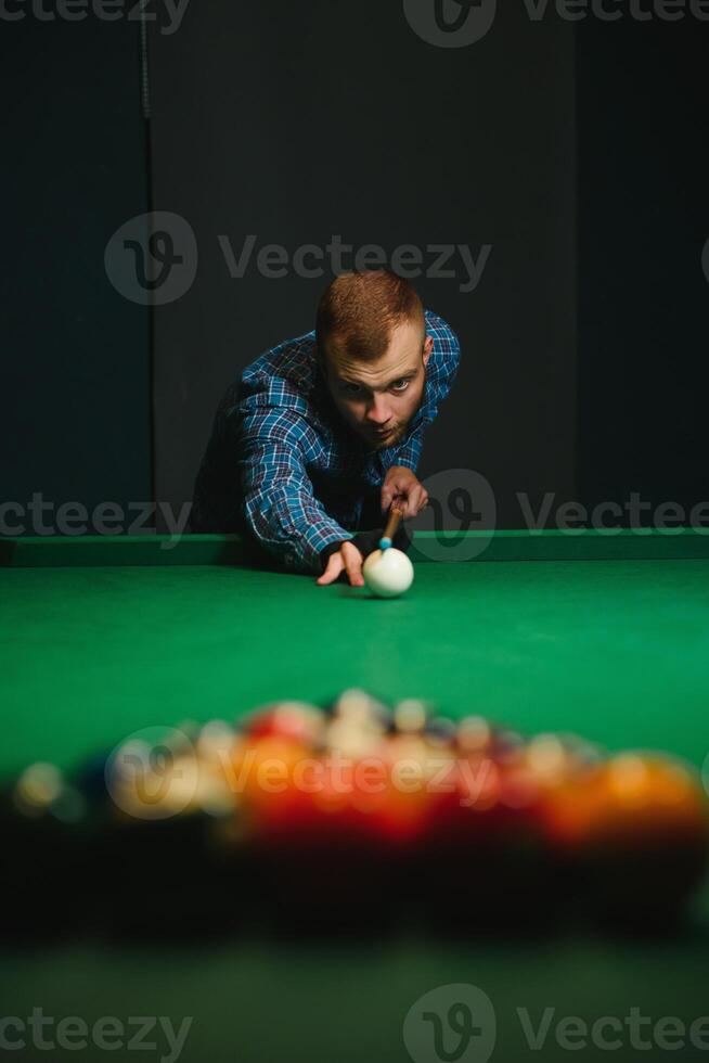 Thoughtful man plays billiards. Billiard room on the background. photo
