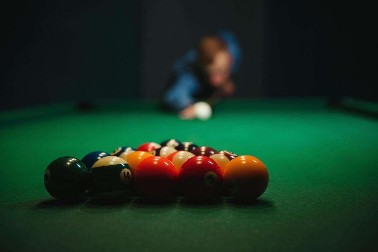 Young man playing billiards in the dark billiard club photo
