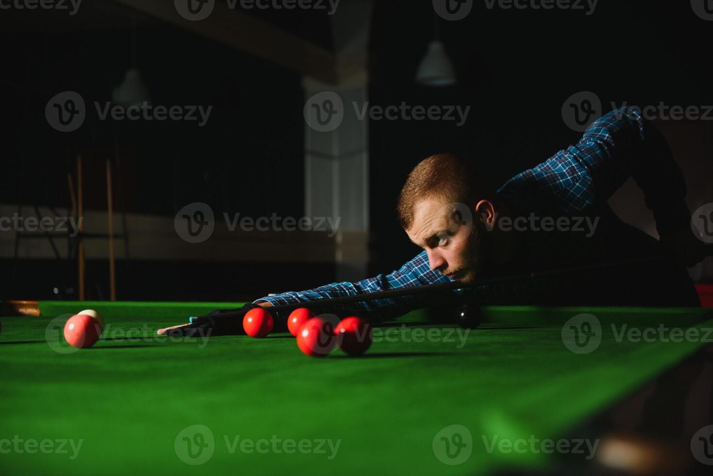 Young man playing billiards in the dark billiard club photo
