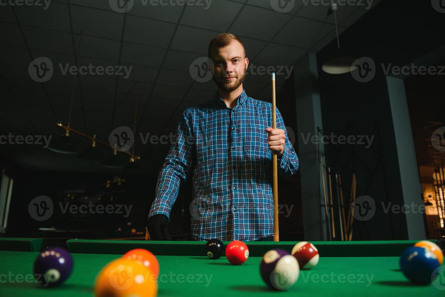 Young man playing billiards in the dark billiard club photo