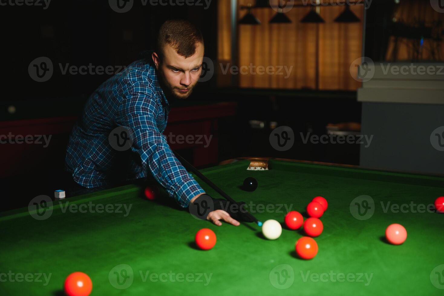 Young handsome man leaning over the table while playing snooker photo