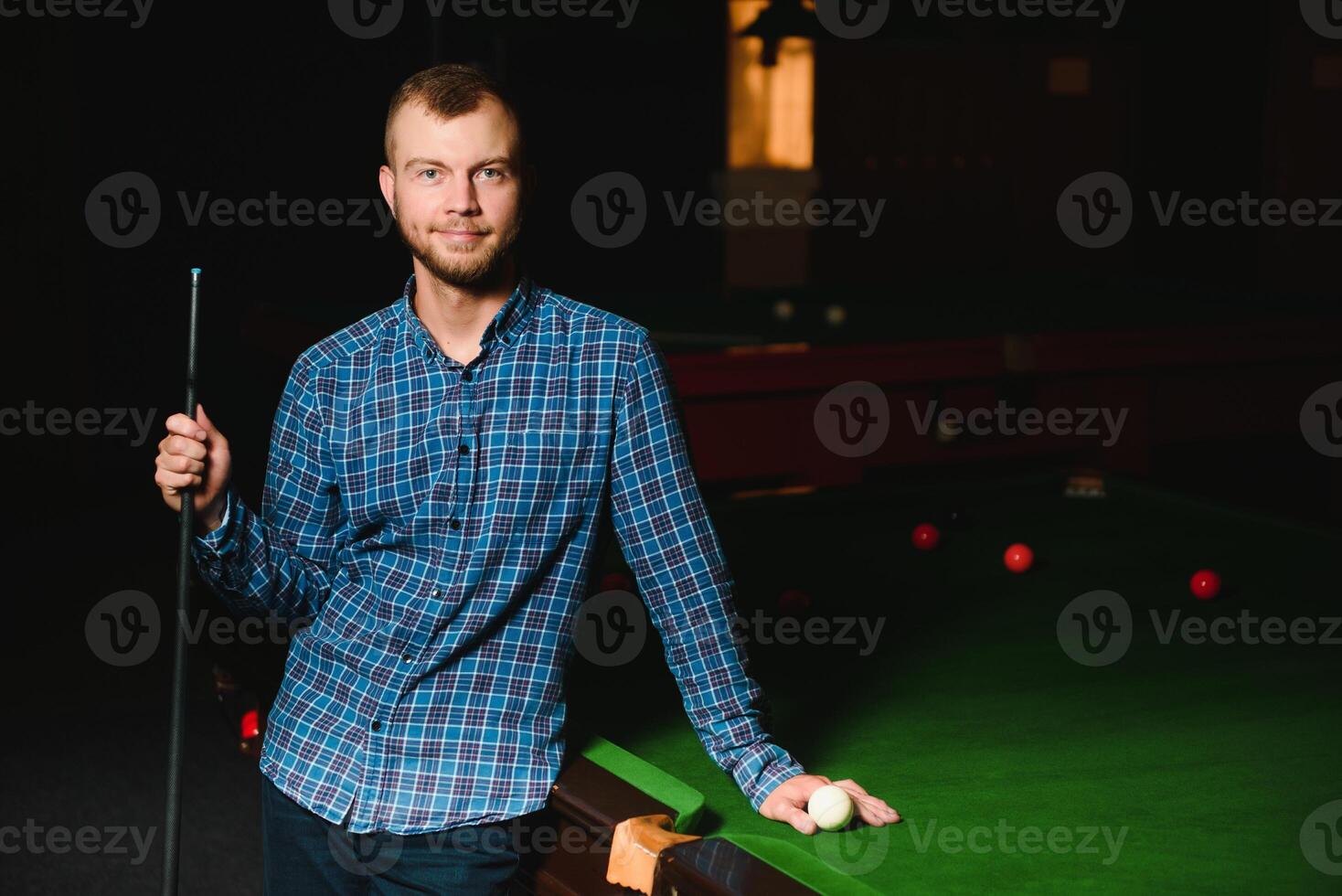 Young man playing billiards in the dark billiard club photo