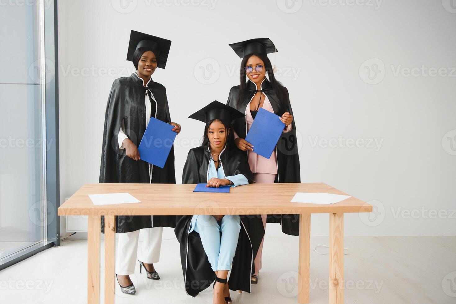 education, graduation and people concept - group of happy international graduate students in mortar boards and bachelor gowns with diplomas photo