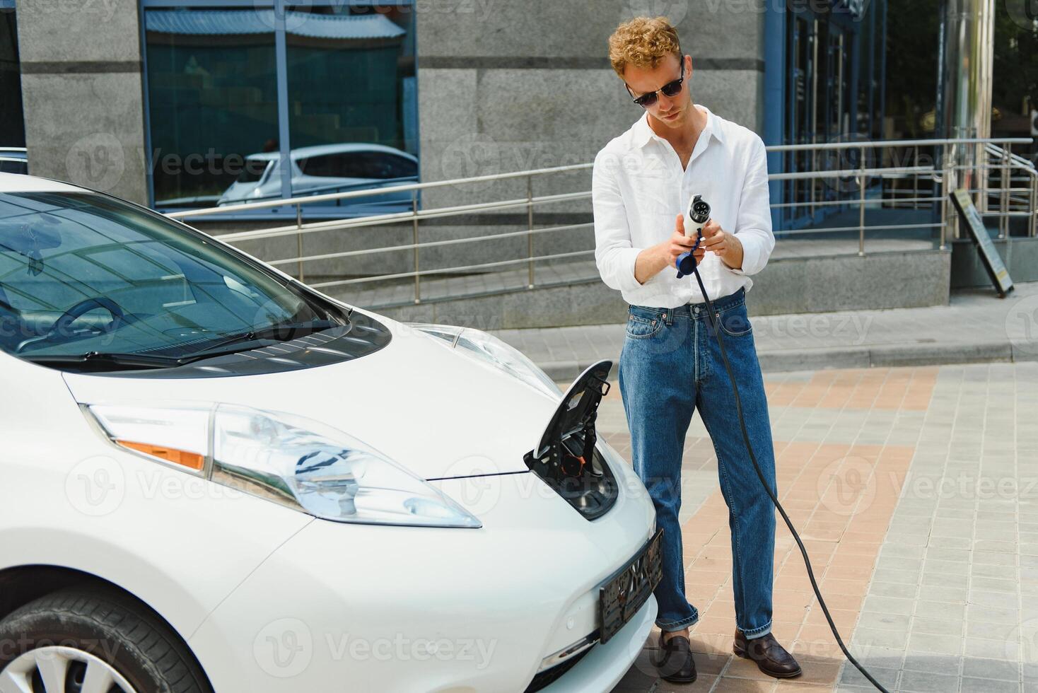 Smiling man unplugging the charger from the car photo