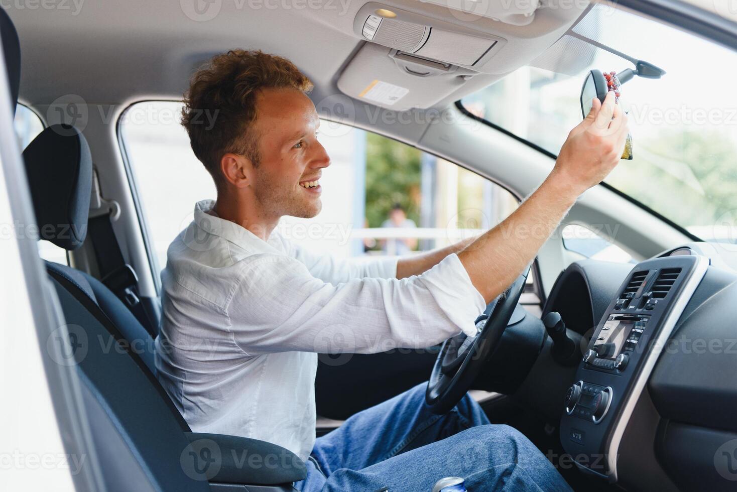 Test driving of new generation electro vehicle with self driving system. Handsome Caucasian man sitting behind the wheel of new modern car and smiling at camera. photo