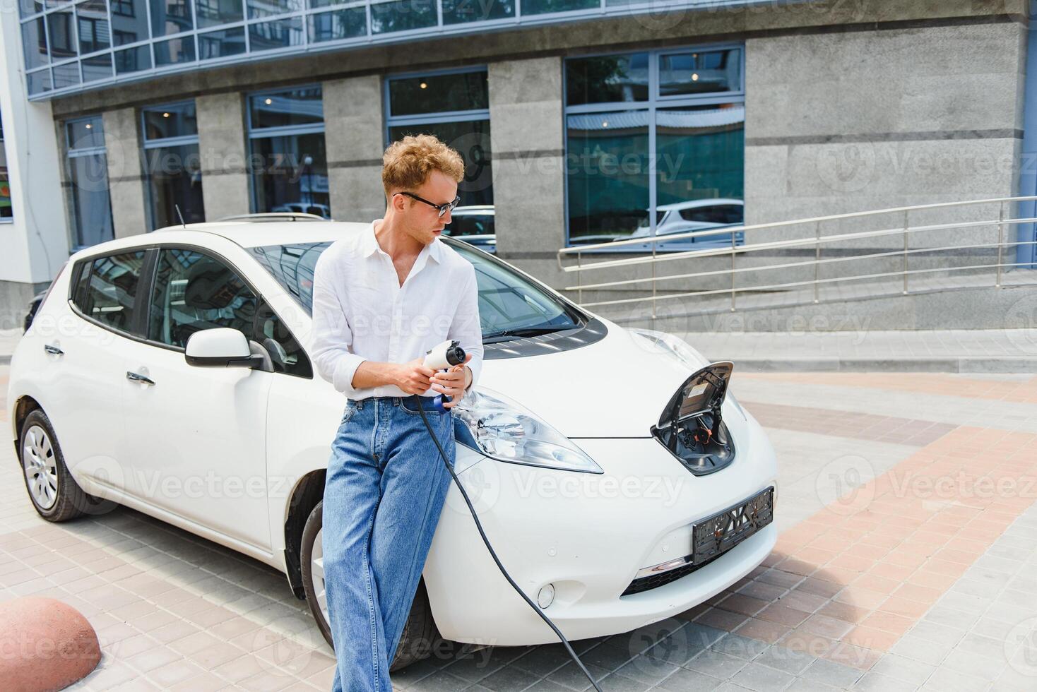 Smiling man unplugging the charger from the car photo