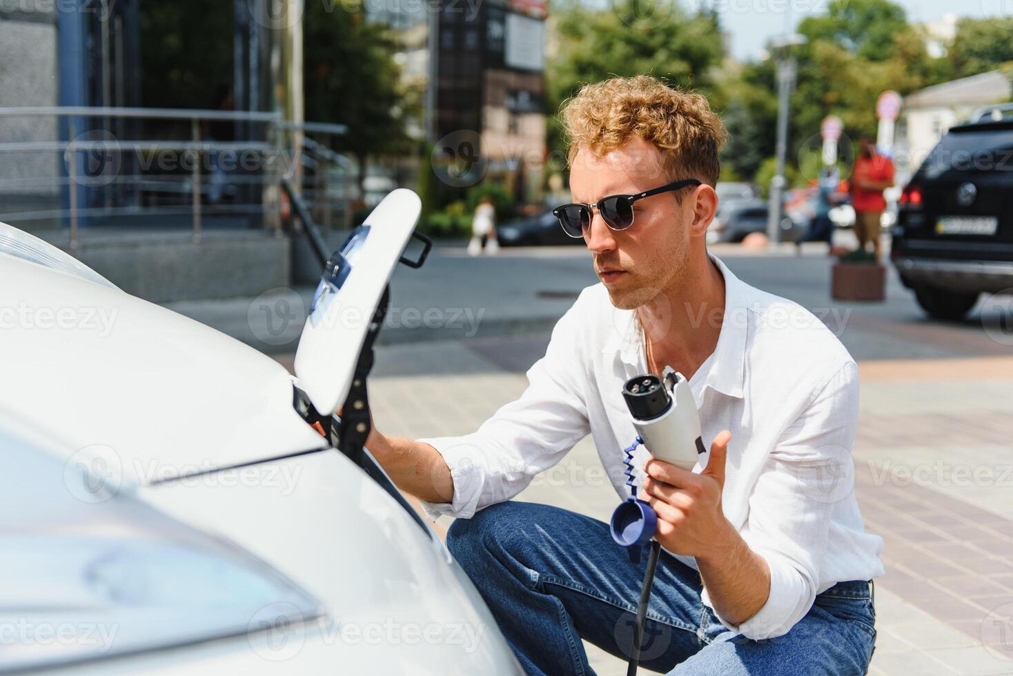 Smiling man unplugging the charger from the car photo
