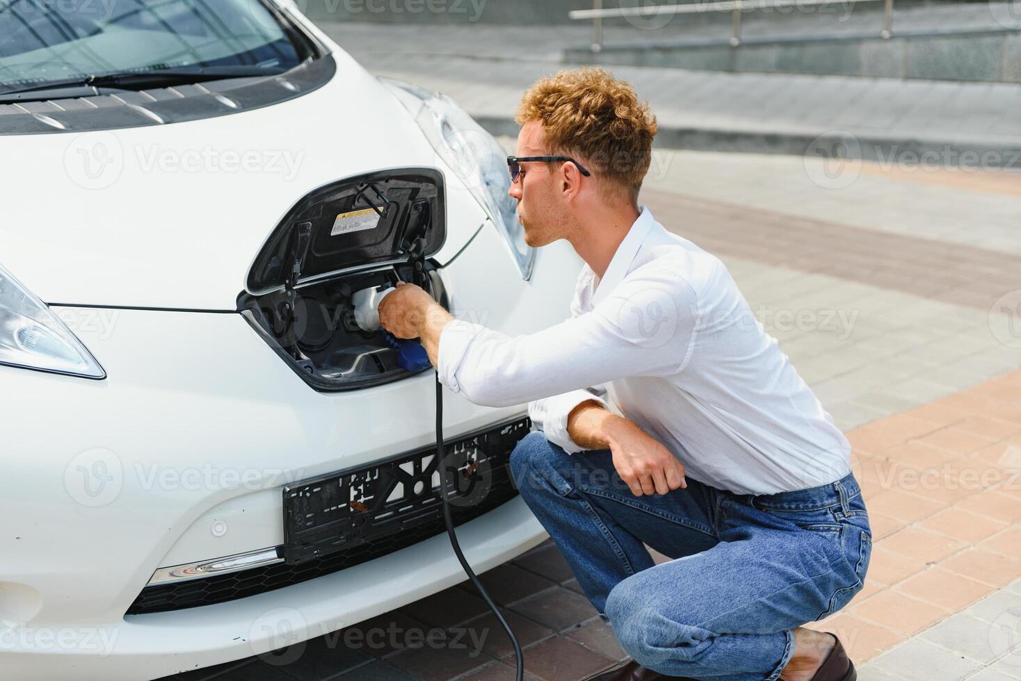 Smiling man unplugging the charger from the car photo