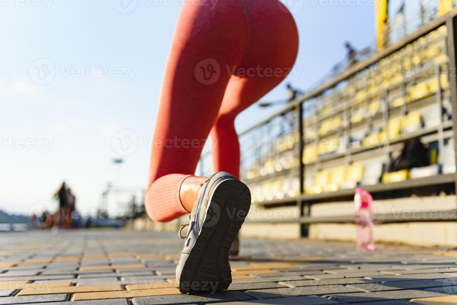 Young woman running during sunny morning on stadium photo