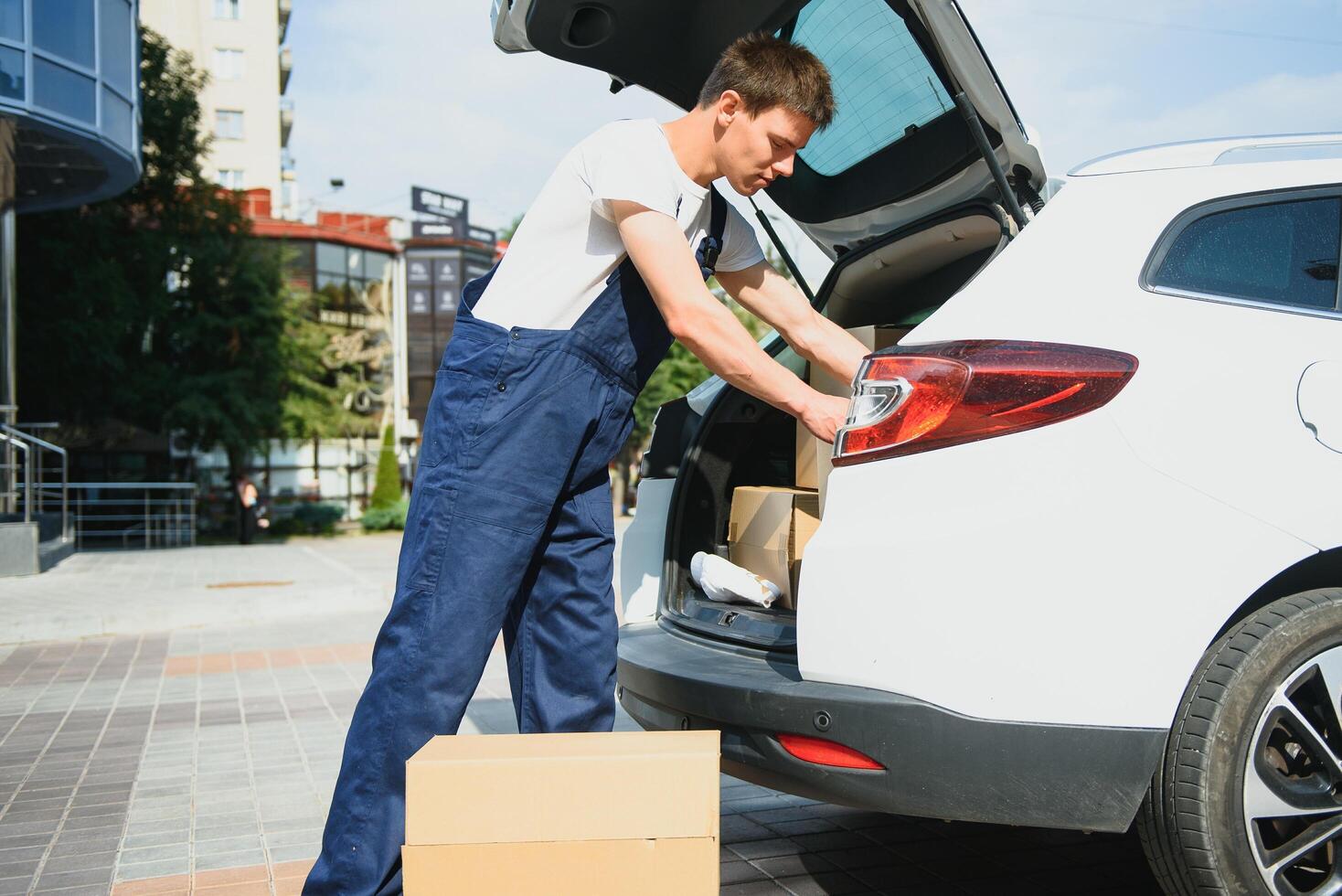Deliveryman holds parcels at the car, delivering photo