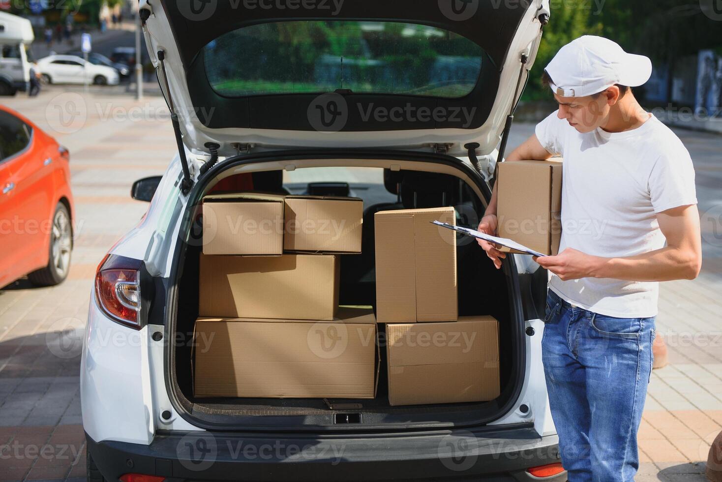 Smiling delivery man standing in front of his car photo