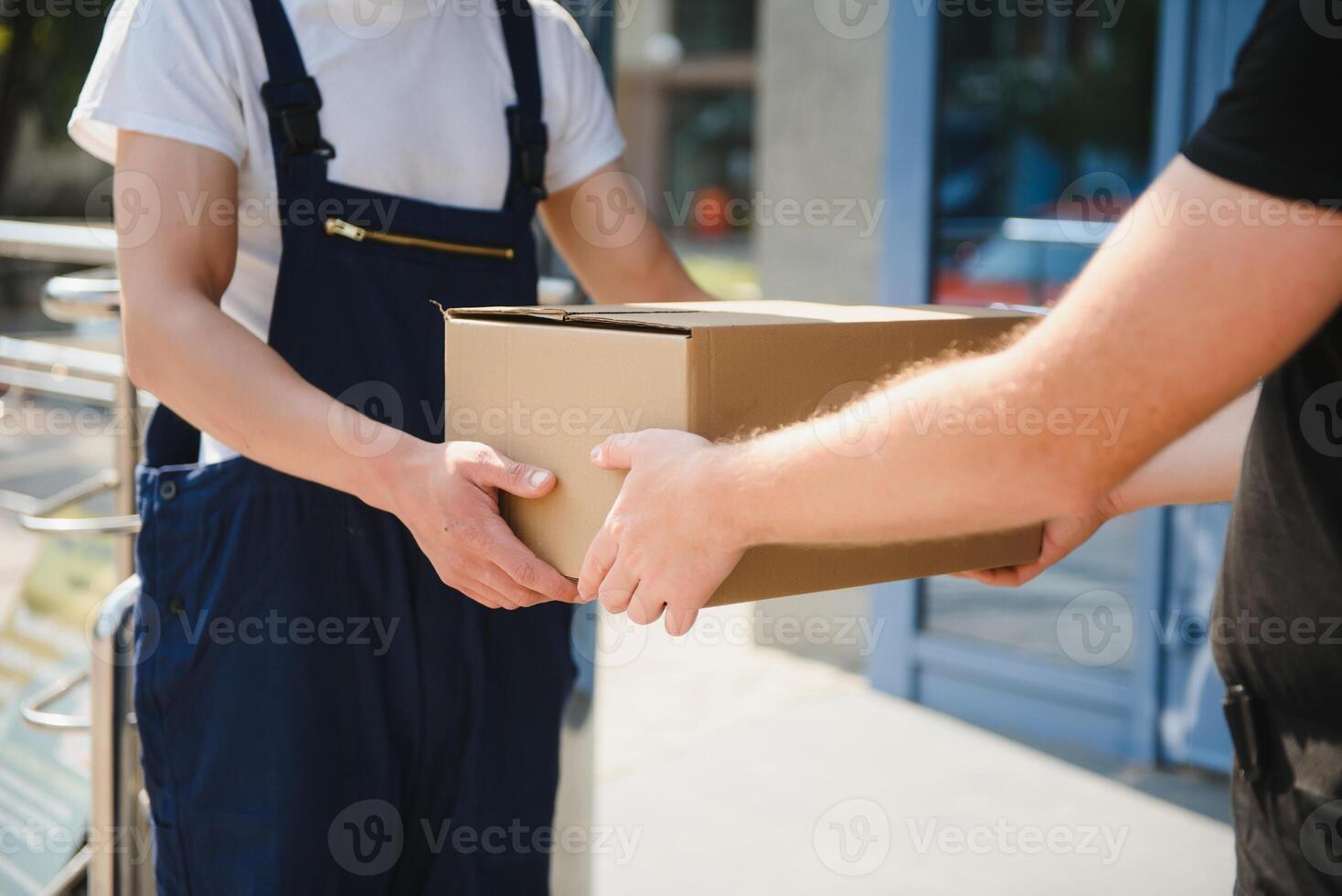 Delivery man service with boxes in hands standing in front of Customer's house doors photo
