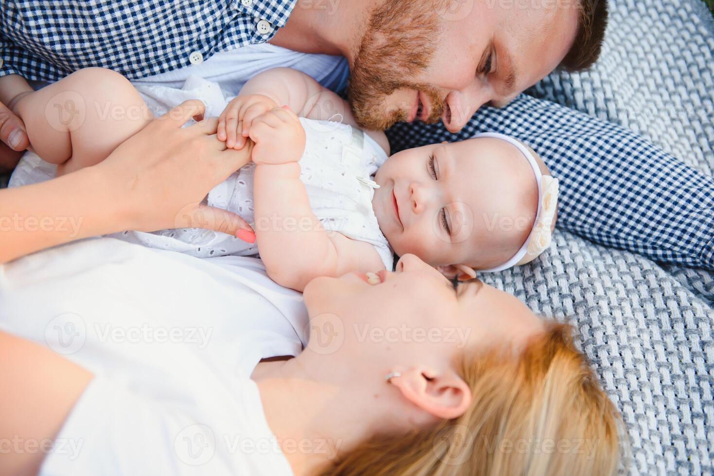 Mom, dad and little son lying on the blanket in the summer park. The concept of summer holiday. Mother's, father's, baby's day. Family spending time together on nature. Family look photo