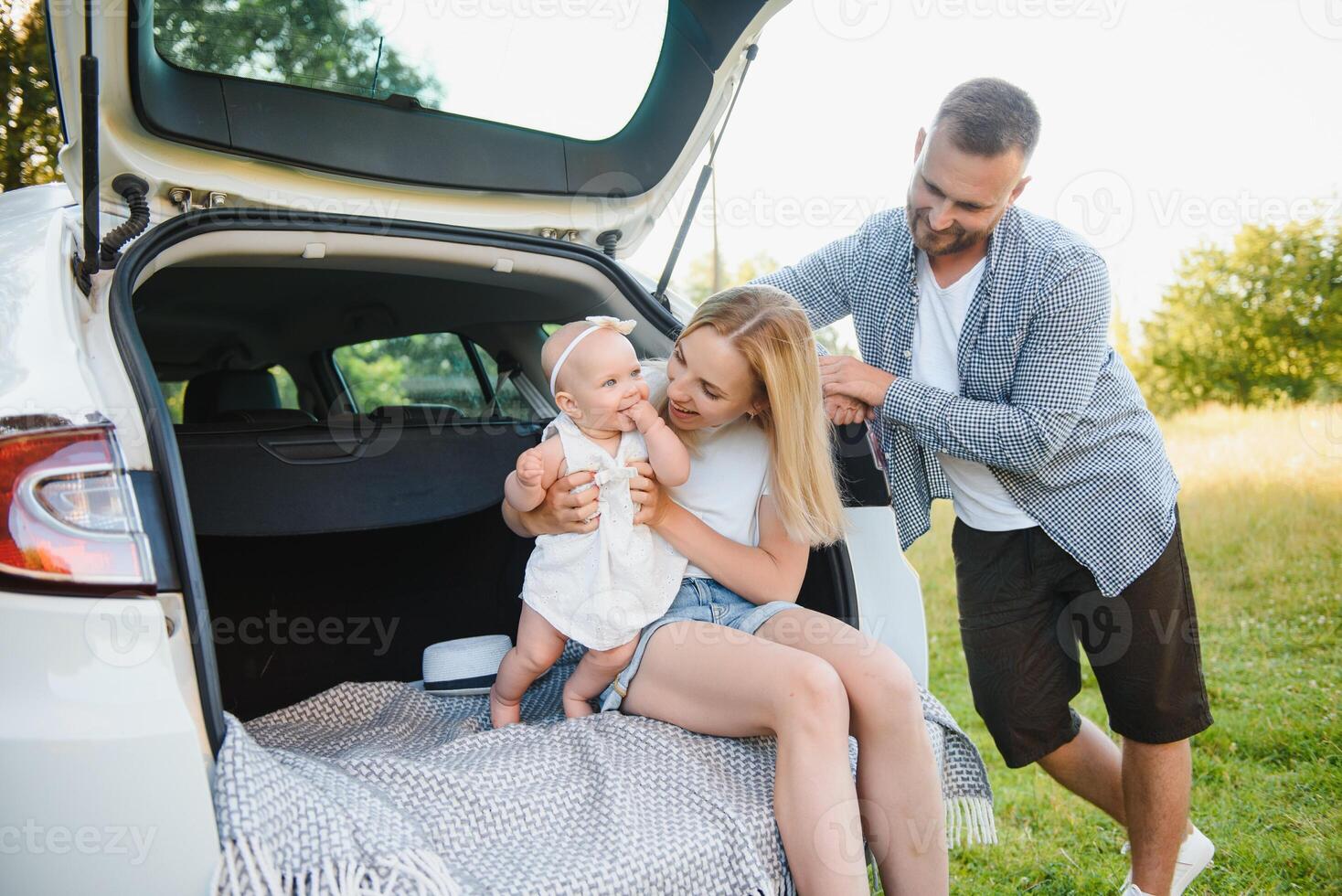 Family with kid sitting in car trunk photo
