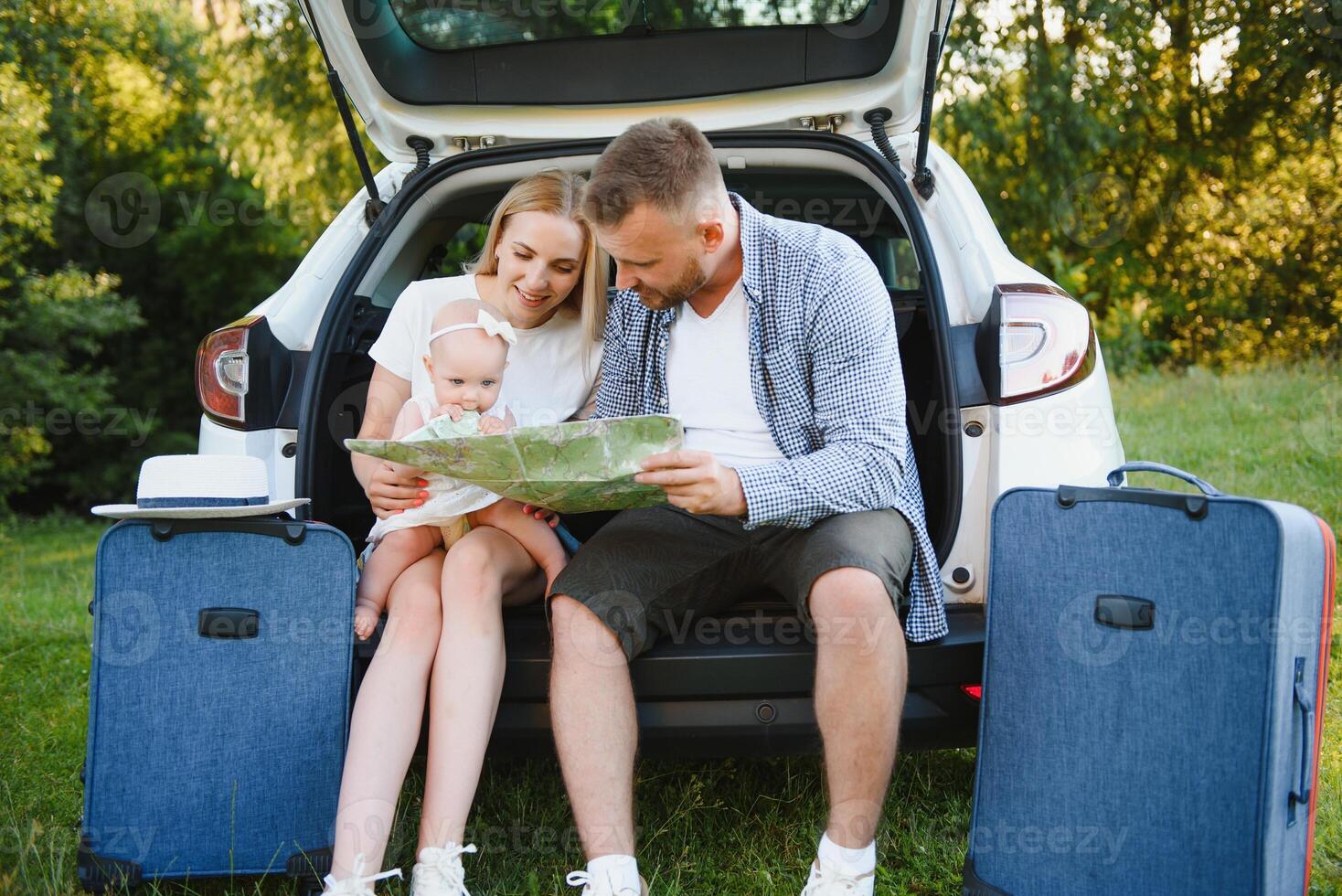 Loving couple hugging sitting in the trunk of the car looking at the map going on a journey photo