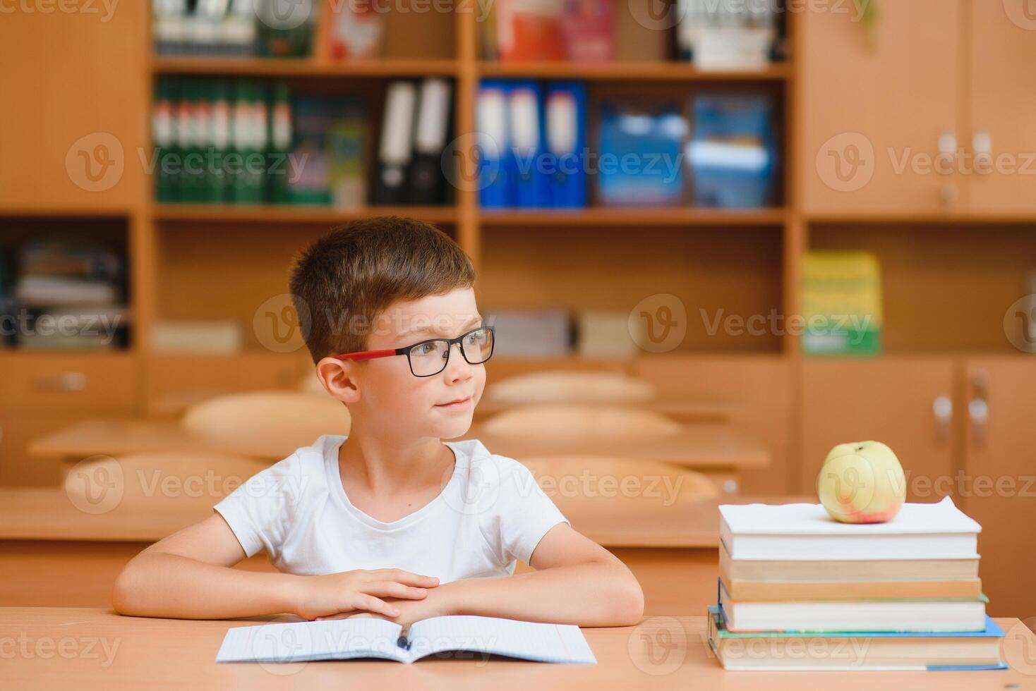 Elementary school boy at classroom desk trying to find new ideas for schoolwork. photo