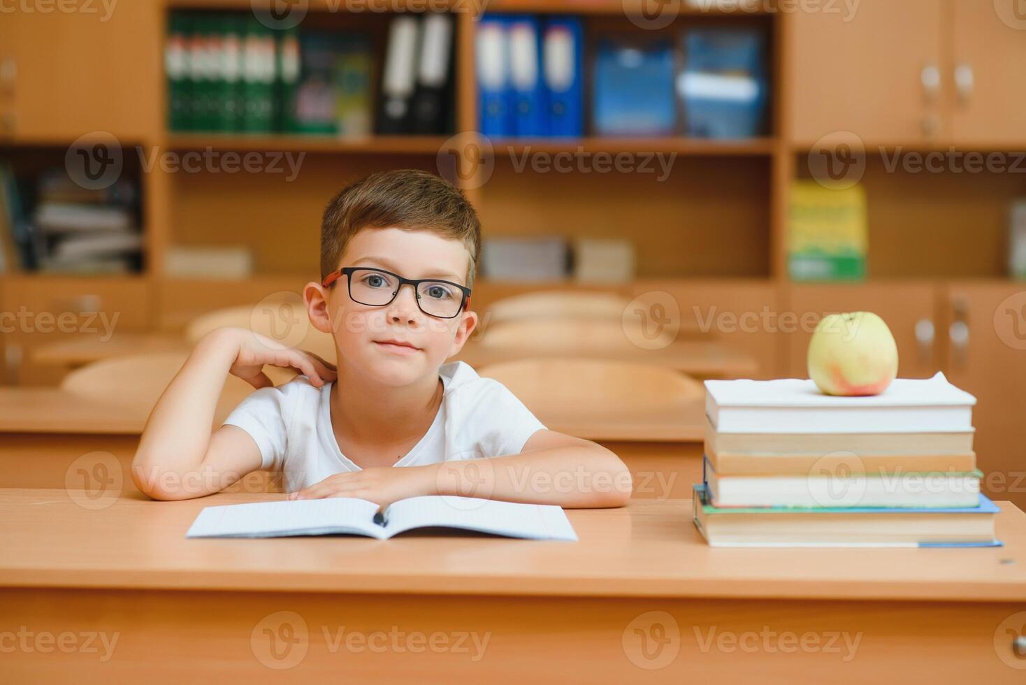 Elementary school boy at classroom desk trying to find new ideas for schoolwork. photo