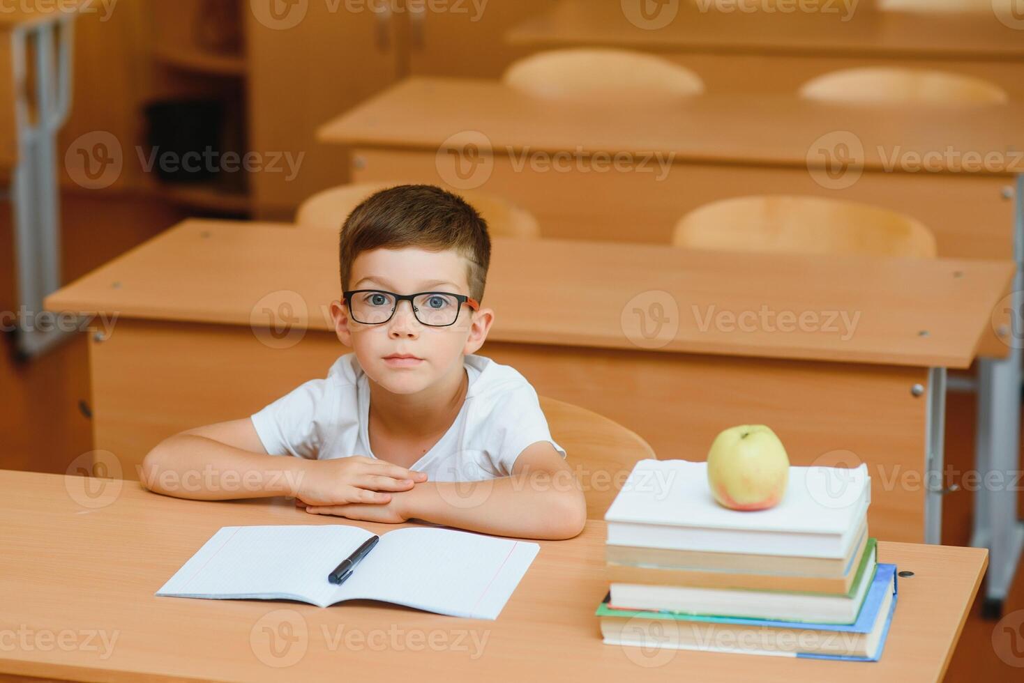 Elementary school boy at classroom desk trying to find new ideas for schoolwork. photo