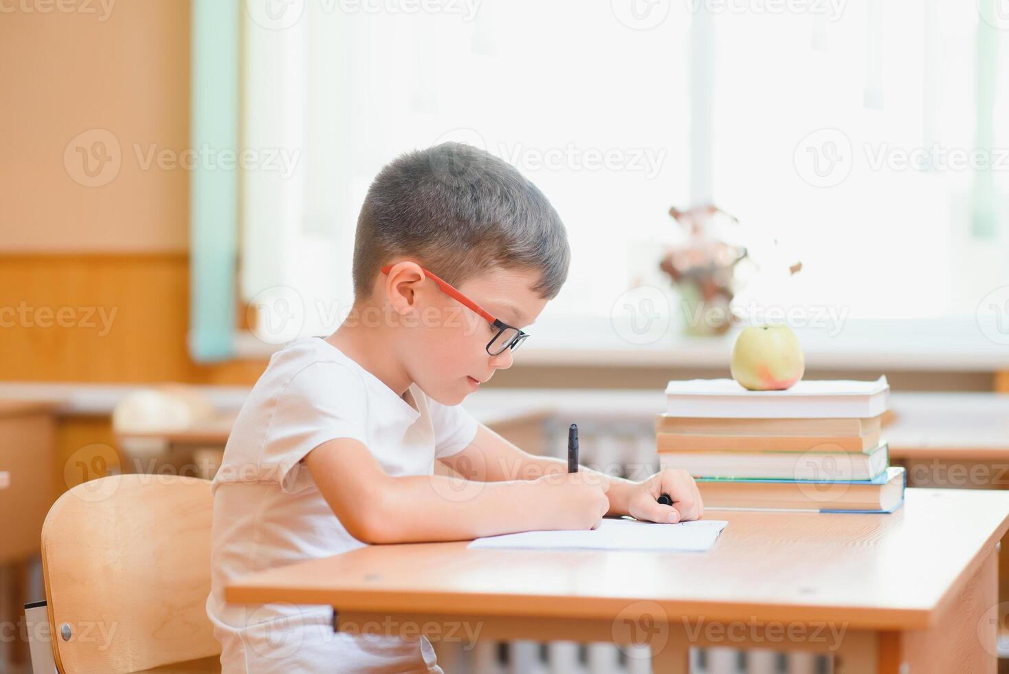 Elementary school boy at classroom desk trying to find new ideas for schoolwork. photo