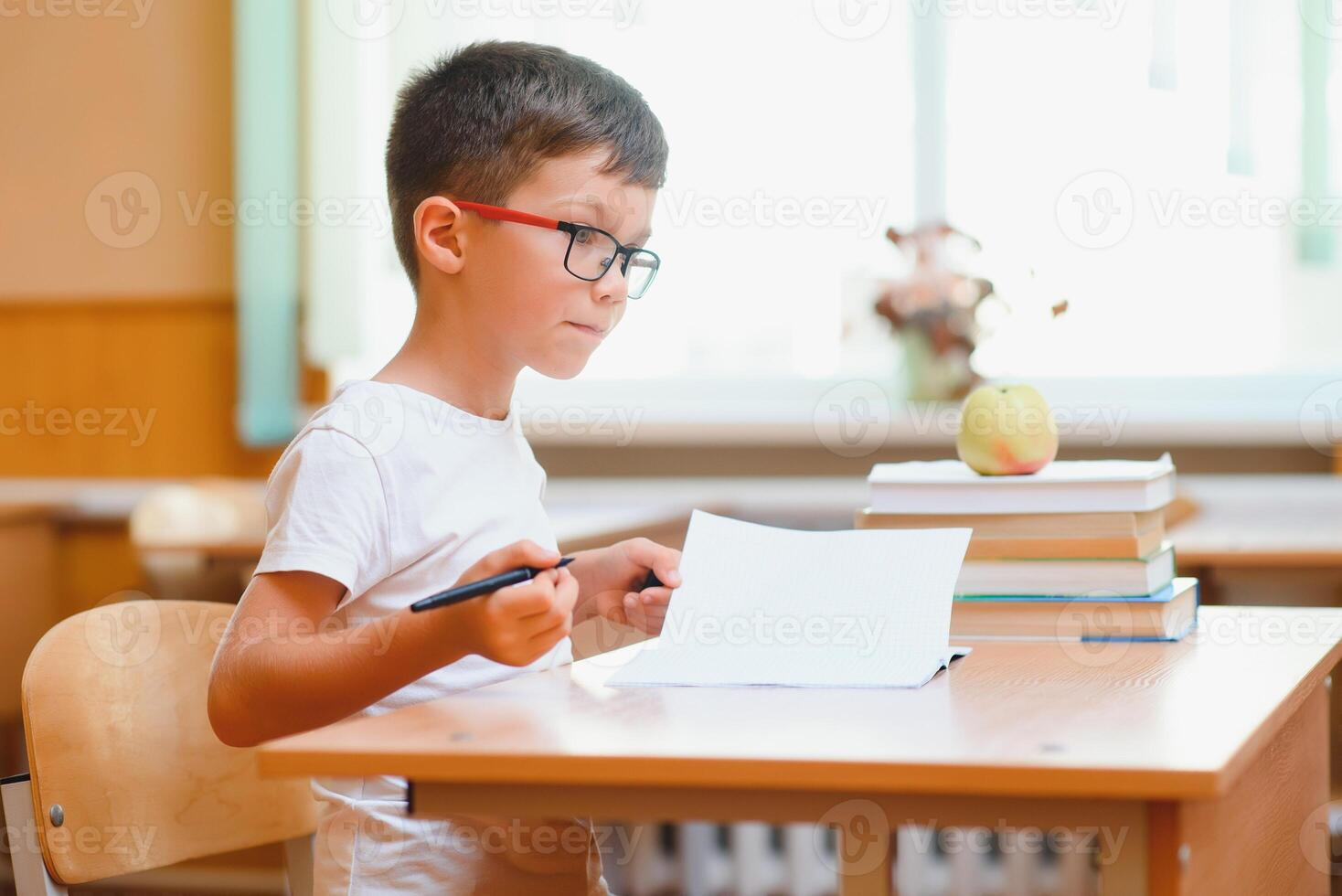 Elementary school boy at classroom desk trying to find new ideas for schoolwork. photo