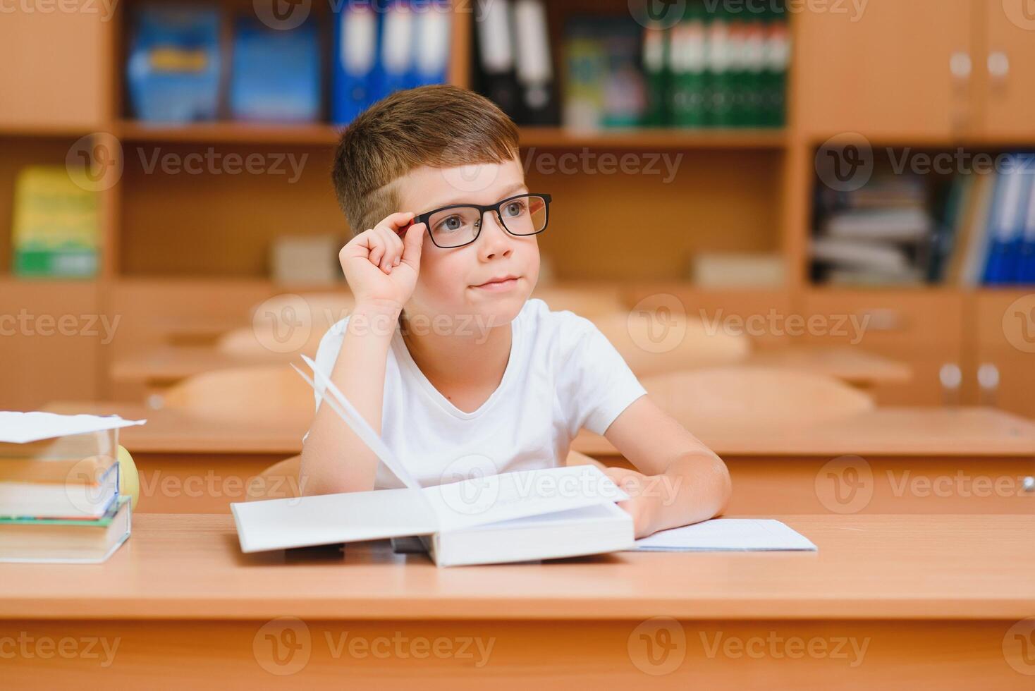 Elementary school boy at classroom desk trying to find new ideas for schoolwork. photo