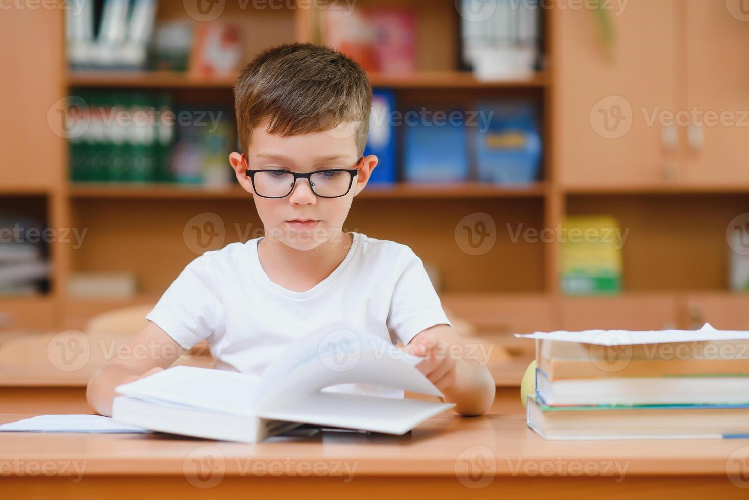 Elementary school boy at classroom desk trying to find new ideas for schoolwork. photo