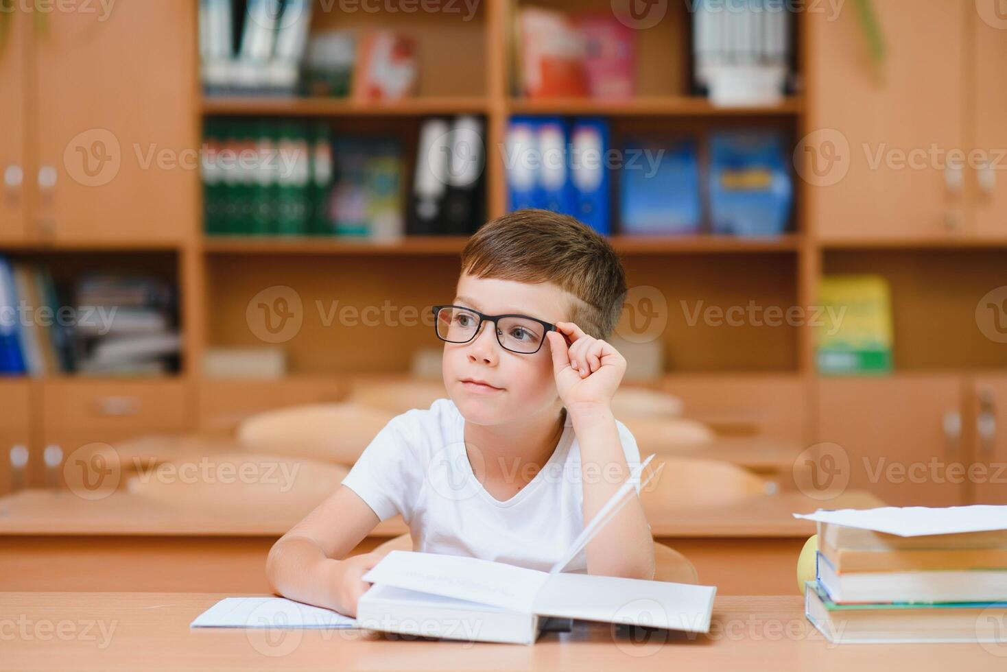 Elementary school boy at classroom desk trying to find new ideas for schoolwork. photo