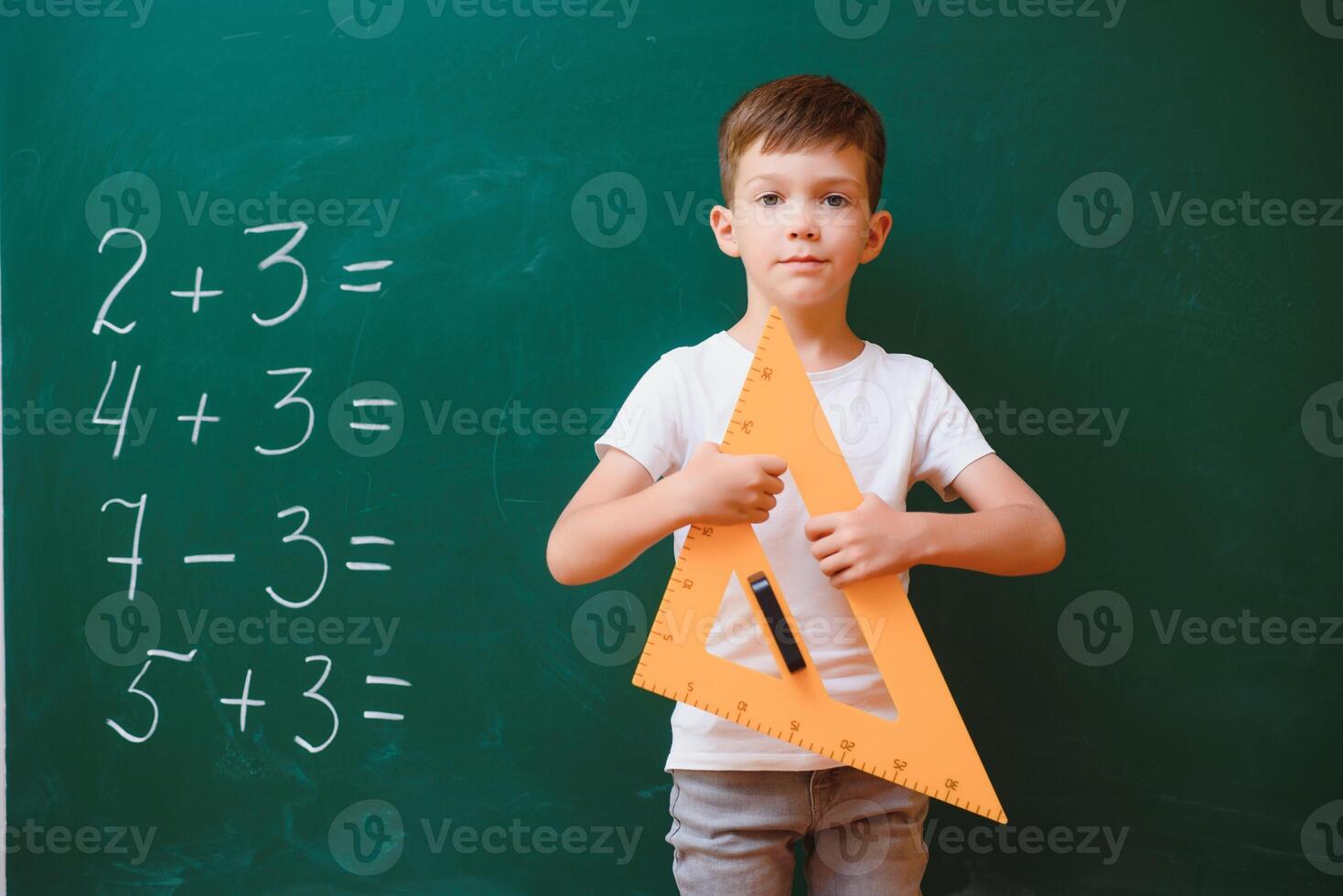 Funny schoolboy near the green school board in the classroom. Elementary school. Back to school. photo