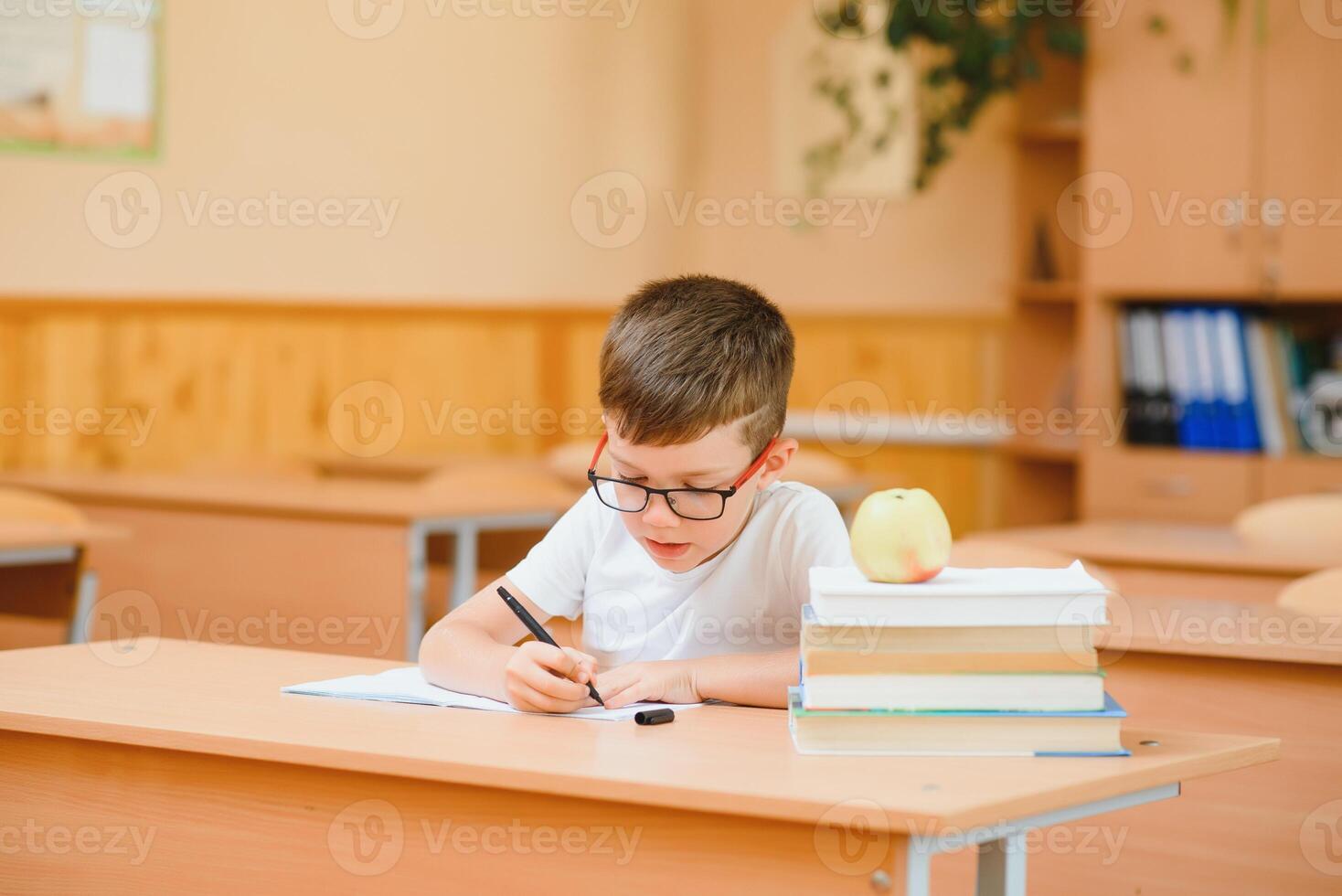 Elementary school boy at classroom desk trying to find new ideas for schoolwork. photo