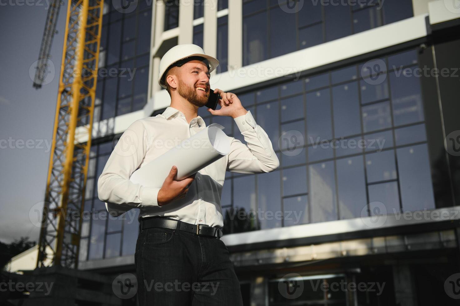 Portrait of man engineer at building site. Male construction manager wearing white helmet and yellow safety vest photo