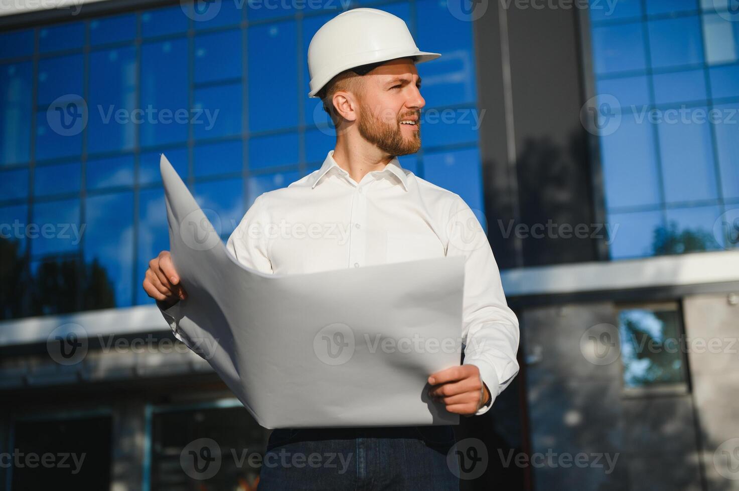 Portrait of man engineer at building site. Male construction manager wearing white helmet and yellow safety vest photo