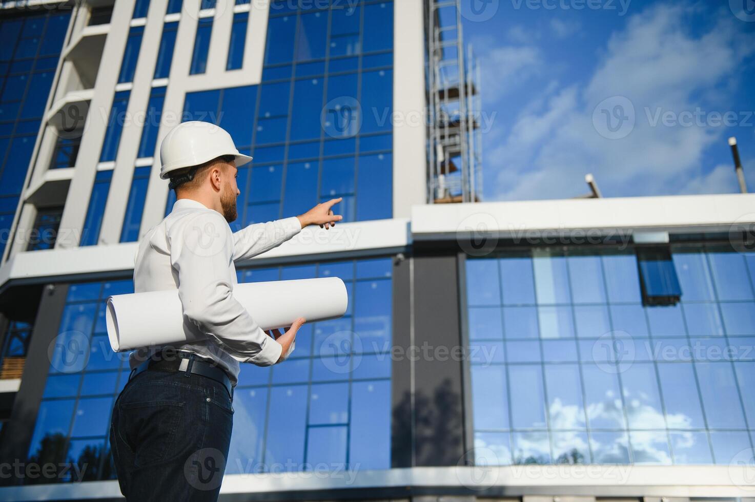 Successful engineer or architect, crane and building construction at backgrpound. Joyous businessman with wearing helmet. photo