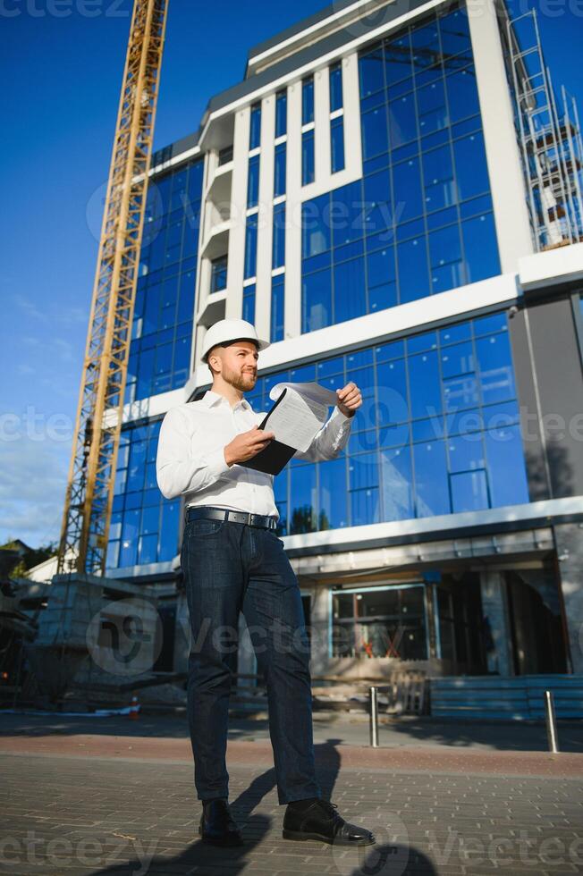 Architect in helmet writing something near new building photo