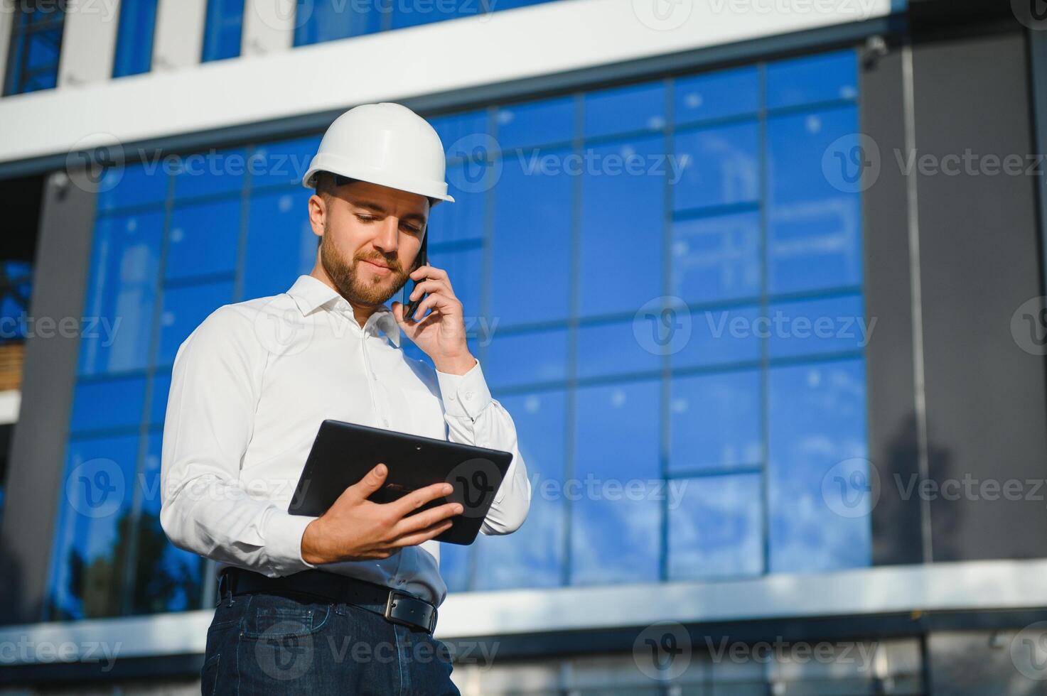 Engineer next to building cranes. Concept - large construction project. Architect directs the construction process. Drawings and tablet in the hands. photo