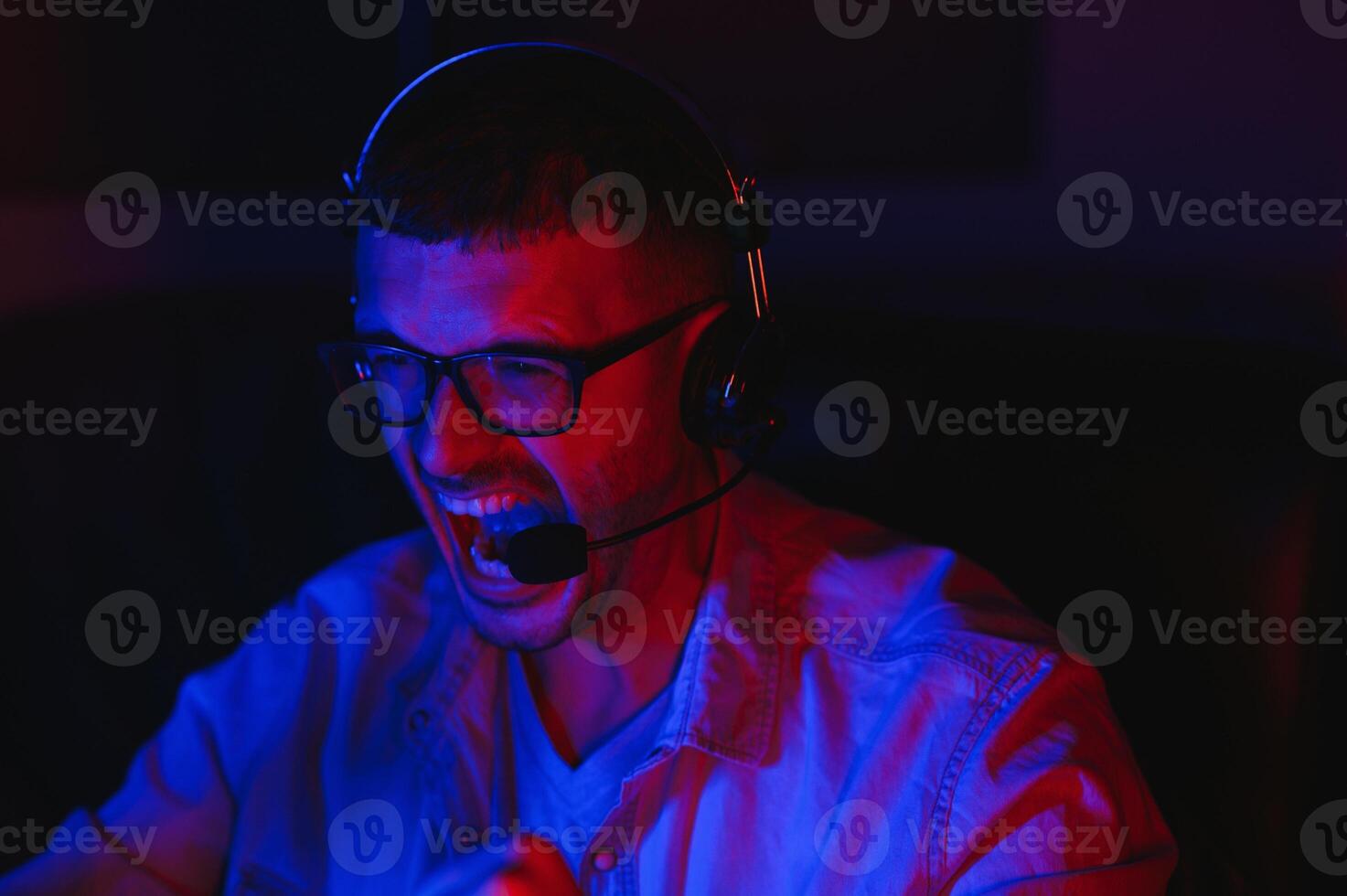 Pro Gamer. Millennial Guy Using Desktop Computer Playing Online Videogame Sitting At Night At Home. Neon Lights, Selective Focus photo