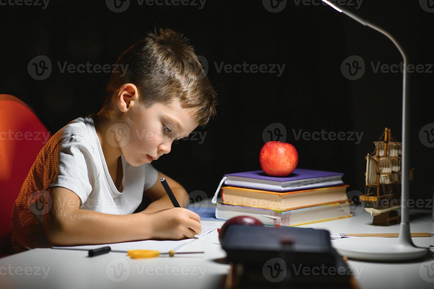 Boy learn lessons in the home setting at the table in the light of a table lamp. photo