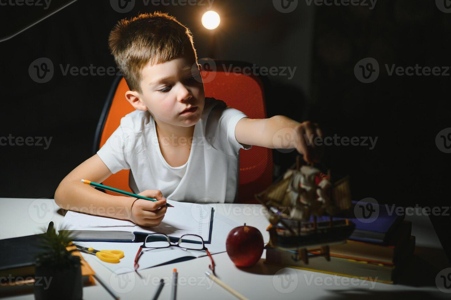 Little boy painting in a dark room late in the evening photo