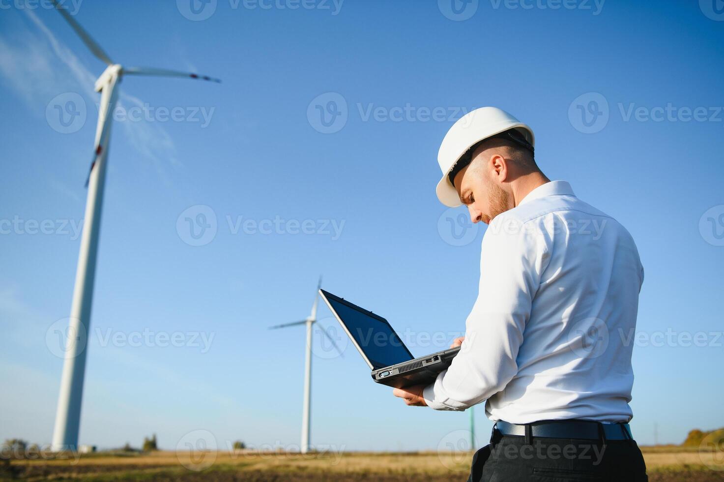 Engineer standing and hoding laptop with wind turbine. photo