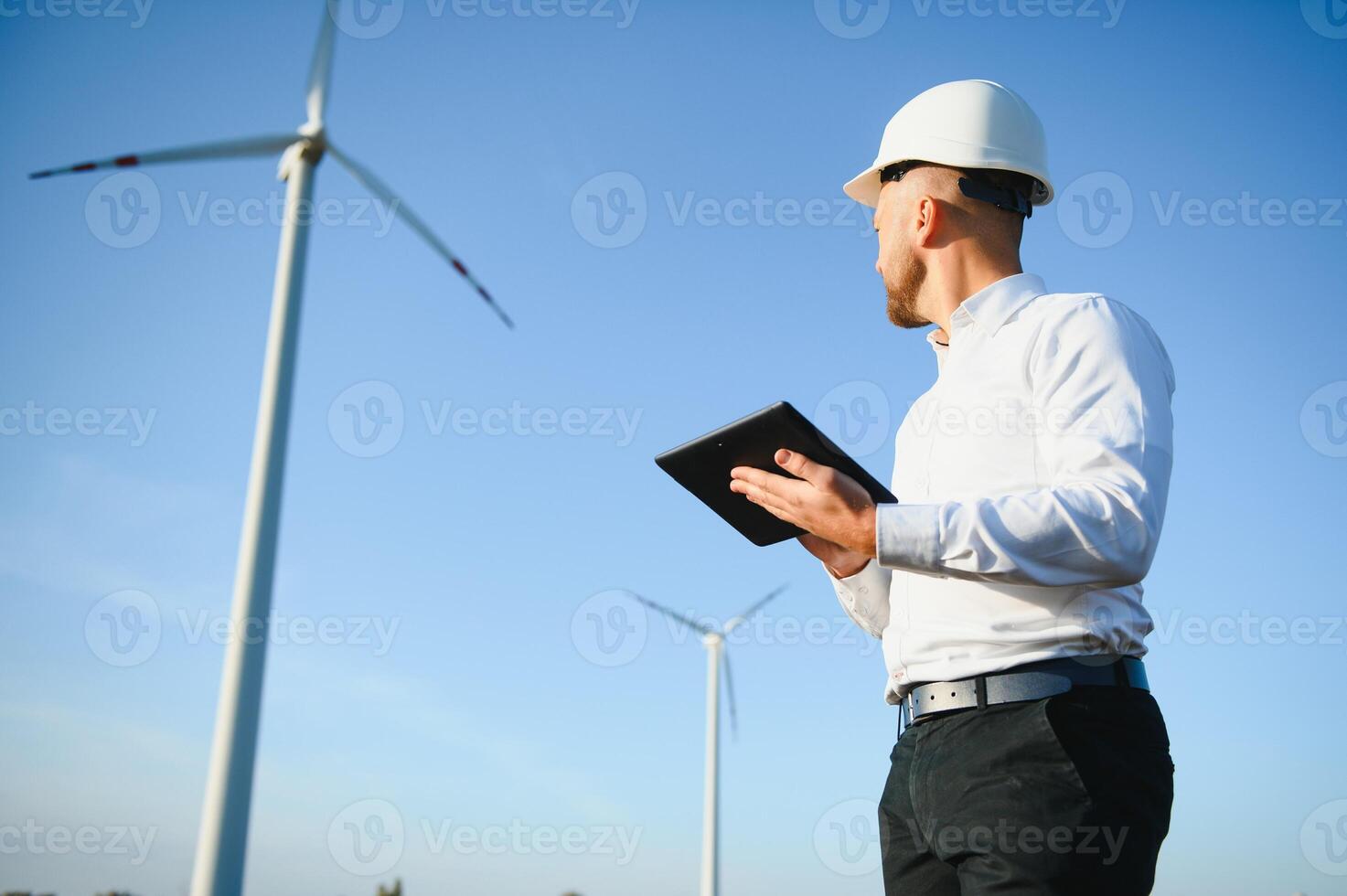 Electrical engineers working at wind turbine power generator station with laptop computer photo