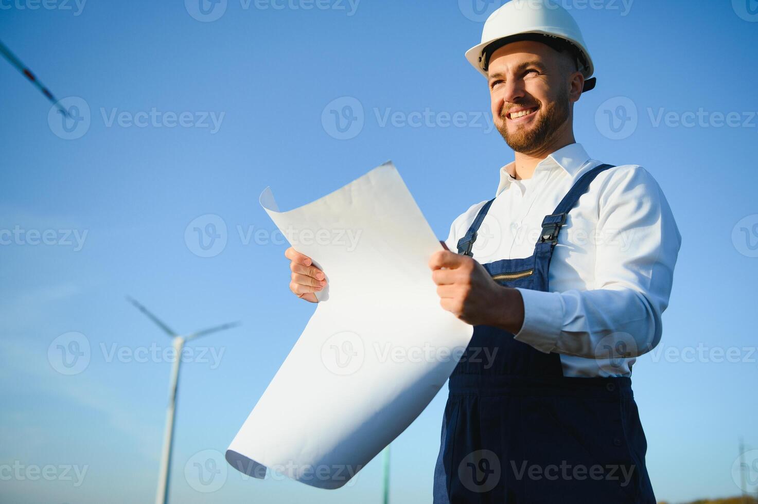 Engineer in wheat field checking on turbine production photo