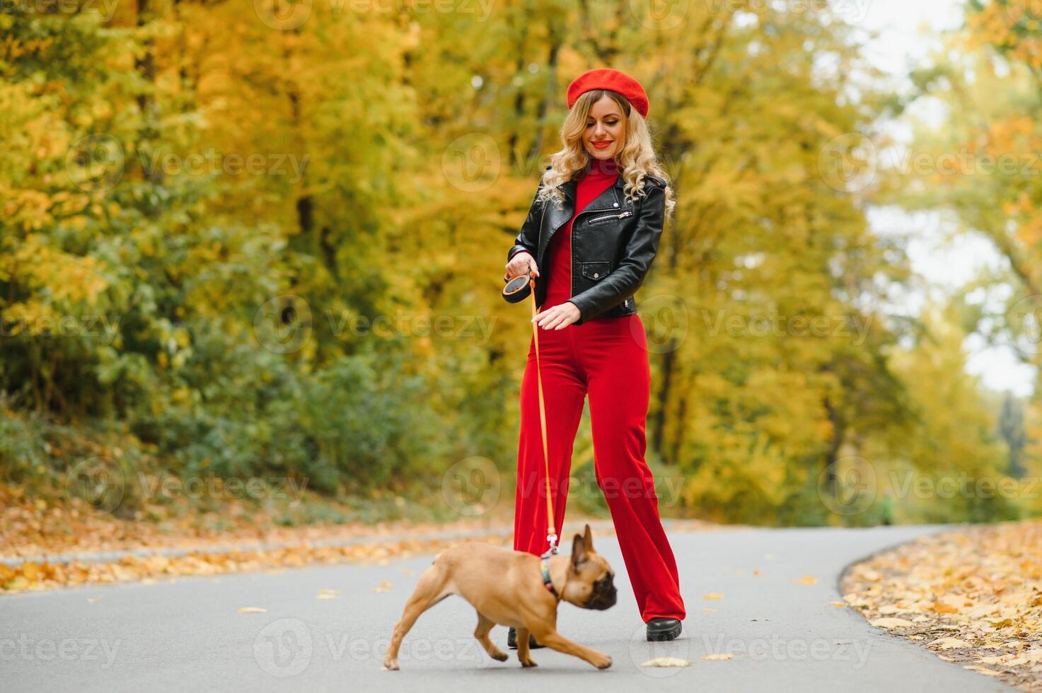 Beautiful and happy woman enjoying in park walking with her adorable French bulldog. photo