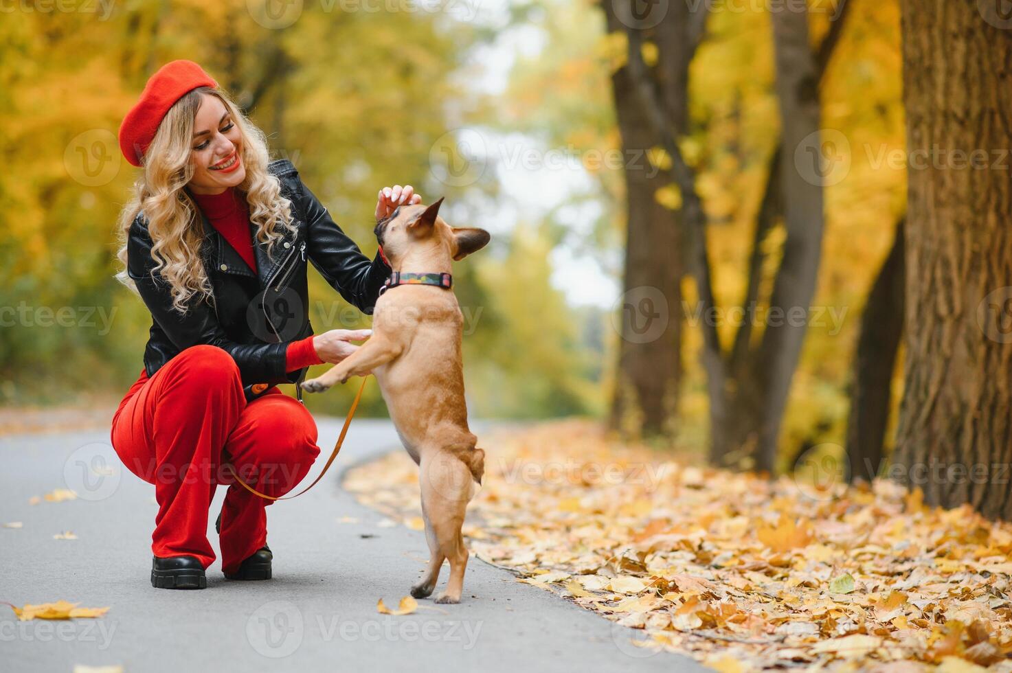 Beautiful and happy woman enjoying in park walking with her adorable French bulldog. photo