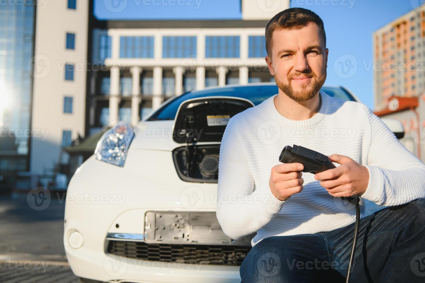 Smiling man unplugging the charger from the car photo