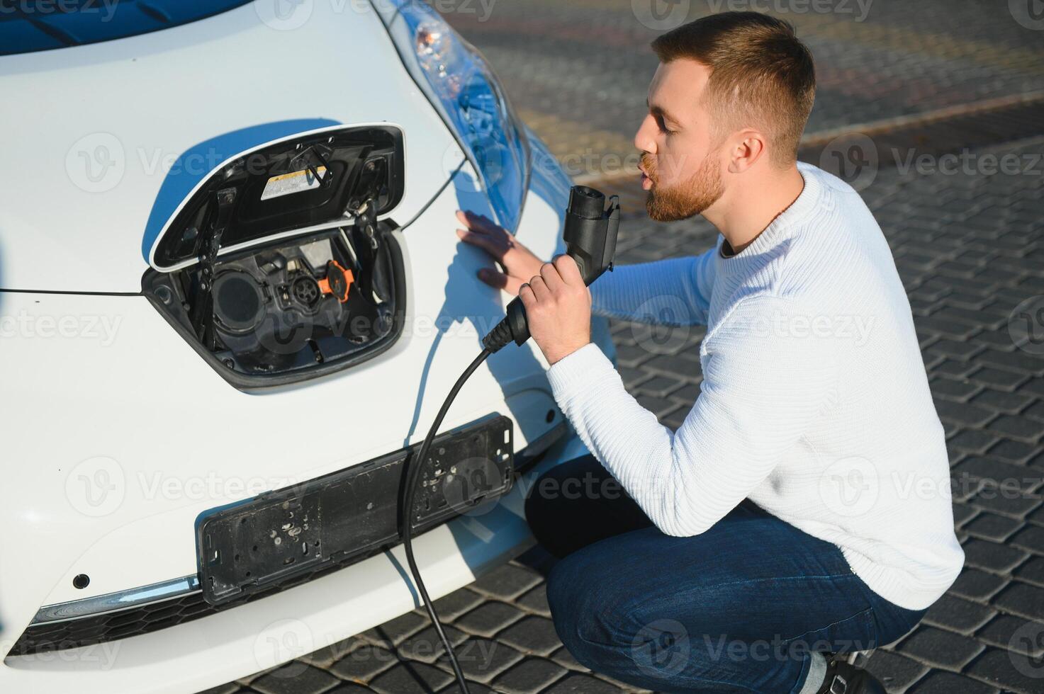 Smiling man unplugging the charger from the car photo