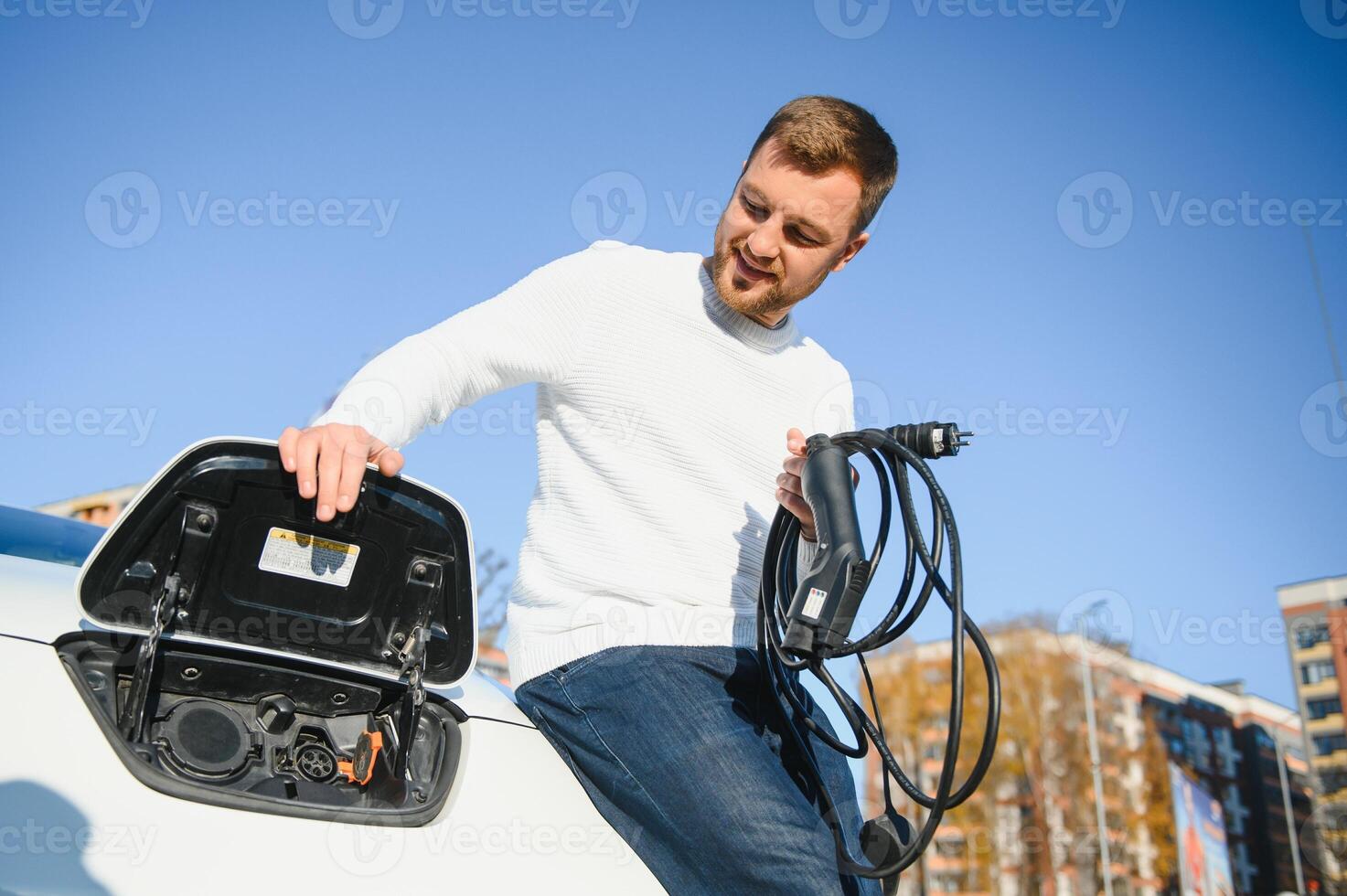 Smiling man unplugging the charger from the car photo
