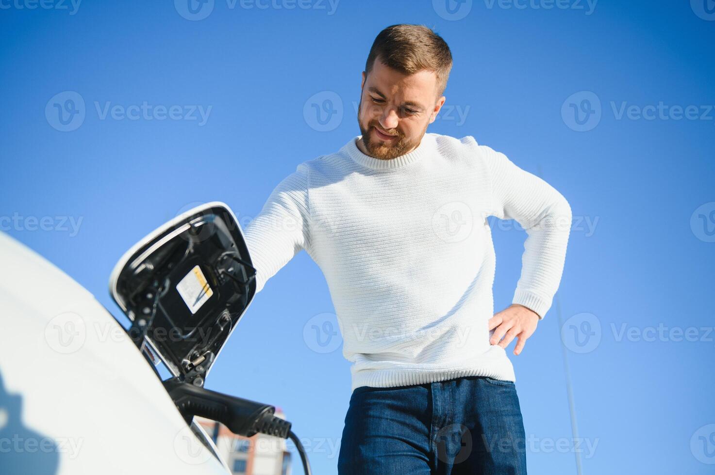 Smiling man unplugging the charger from the car photo